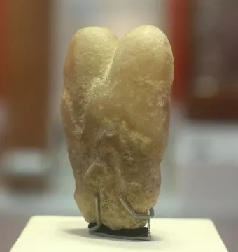 Ain Sakhri Lovers stone sculpture on a metal stand.