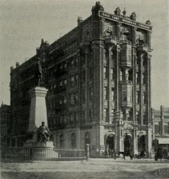 Brigham Young Monument with a standing figure on a tall pedestal and a seated figure below, surrounded by a low fence.