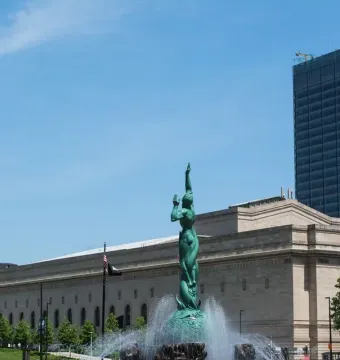 Fountain of Eternal Life sculpture rising from a water basin with downtown Cleveland buildings behind it.