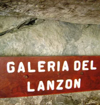 Wooden Galeria del Lanzón sign mounted against a rough stone wall.