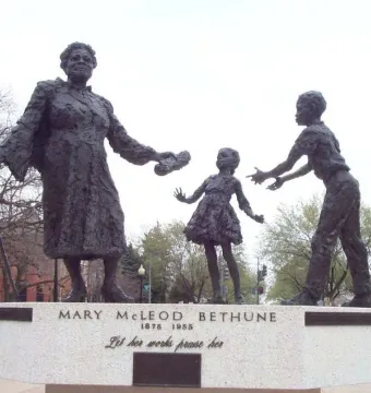 Mary McLeod Bethune Memorial statue showing a woman with a cane and object facing two children on a stone base.