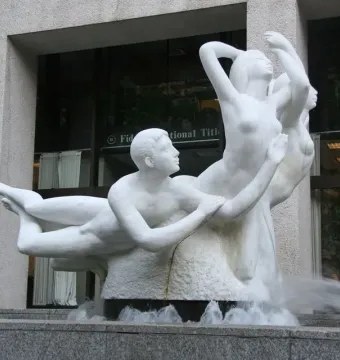 The Quest sculpture, a white marble fountain with nude figures and water flowing into a granite basin.