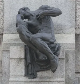 Detail of the Antonio Maceo Monument showing a seated bronze figure in a pensive pose against a carved stone backdrop.