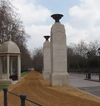Commonwealth Memorial Gates with stone pillars, urns, and a domed pavilion beside a paved path.