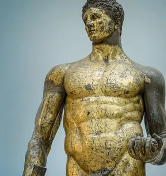 Hercules of the Forum Boarium, a gilded bronze nude male statue holding a club and three round objects.