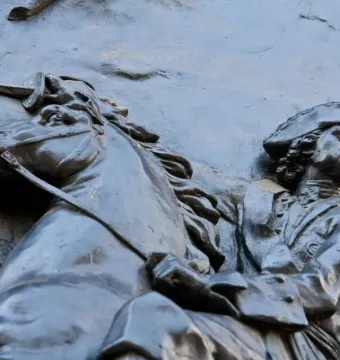 Bronze relief from the Monument to Peter I showing a horseman in historical military attire and a tricorn hat.