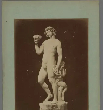 Marble statue of Bacchus with a small satyr at his side, holding a cup and wearing a grape wreath.