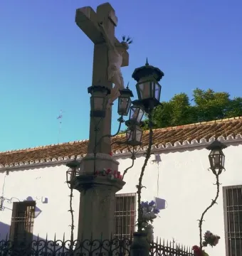 Christ of the Lanterns crucifix with ornate lanterns and a spiked fence in front of a white building
