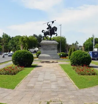 El Cid equestrian statue on a stone pedestal in a landscaped roundabout.