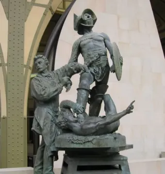 The Gladiators sculpture showing a man sculpting two fighters, one standing victorious over a fallen opponent.