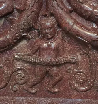 Close-up of the Sarcophagus of Constantina showing a winged putto holding a garland among intertwined relief figures and sea creatures.