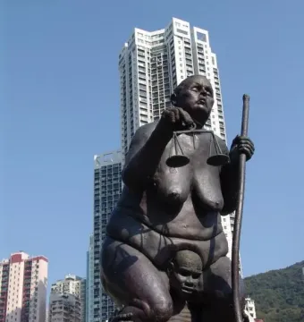 Survival of the Fattest bronze sculpture of an obese woman holding scales and a staff atop an emaciated man.