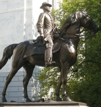 General Joseph Hooker statue on horseback beside a stone building and trees