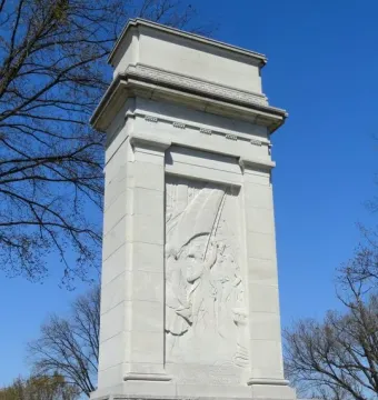 John Paul Jones Memorial with a tall stone shaft, relief figures, and decorative friezes against a blue sky.