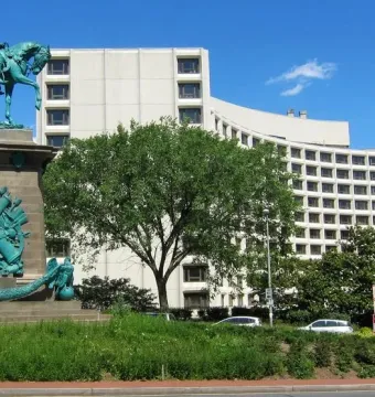Major General George B. McClellan equestrian statue on a carved stone base, with a curved hotel building behind it.
