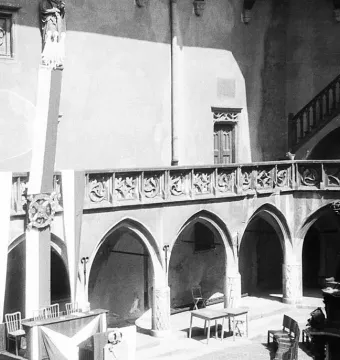 Copernicus Monument in a gothic courtyard, showing a robed statue holding a spherical instrument on a decorated pedestal.