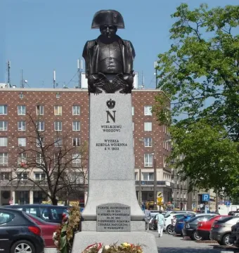 The Emperor Napoleon I Memorial, a tall stone monument with a bronze bust of Napoleon in a bicorne hat and military uniform.