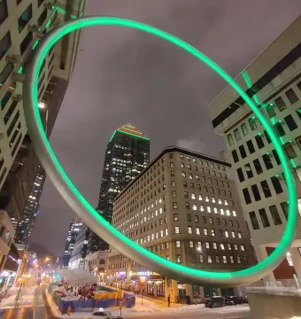 The Ring glows green above a nighttime cityscape with a wet, snowy street below.