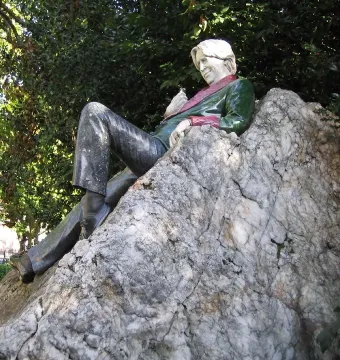 Oscar Wilde Memorial Sculpture of a reclining figure with light hair on a large rocky boulder.