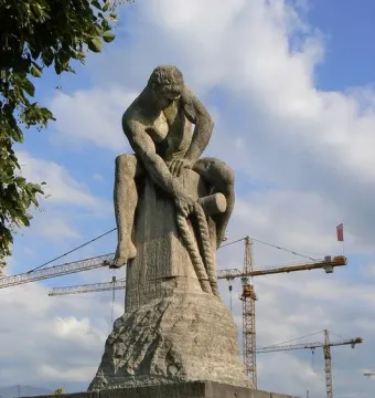 Tauzieher stone sculpture of a muscular man pulling a rope around a stone post.