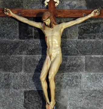 Brunelleschi Crucifix showing a light-colored crucified Christ figure on a dark wooden cross against a stone wall.