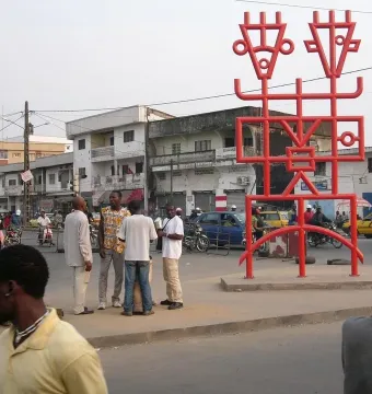 Njé Mo Yé, a large red abstract metal sculpture with two head-like forms on top.