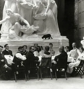 The Fountain of the Great Lakes sculpture stands behind a group of diners seated at a table, with a black cat on the sculpture base.