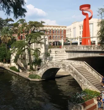 La Antorcha de la Amistad rising above a stone bridge in downtown San Antonio.