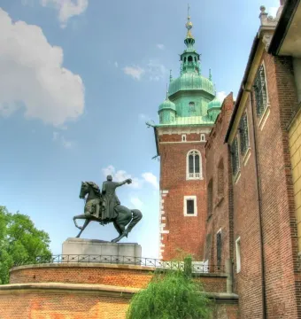 Tadeusz Kościuszko Monument beside a brick building with a green-domed tower at Wawel Castle.