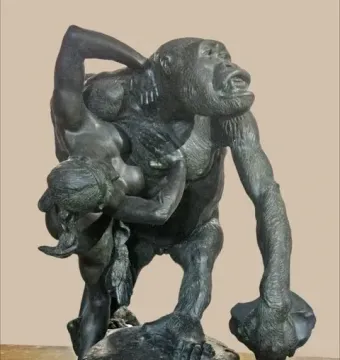 Gorilla Carries a Woman sculpture showing a gorilla standing upright with a woman slung over its shoulder, holding a rock on a rocky base.