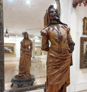Mephistopheles and Margaretta wooden sculpture with a bearded man in elaborate attire and a mirrored reflection of a woman in a long gown