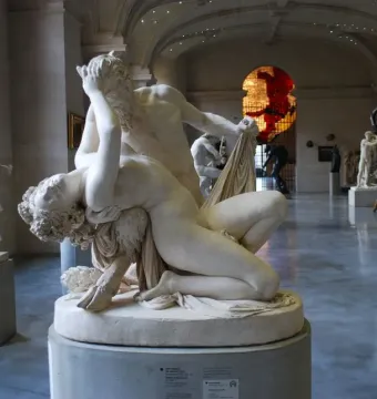 Satyre et bacchante marble sculpture showing two intertwined figures in a museum hall
