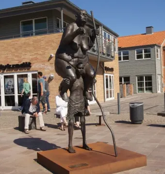 Survival of the Fattest bronze sculpture showing a large woman carrying scales and a staff on the shoulders of an emaciated figure.