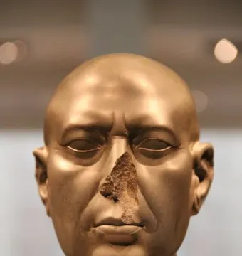 Berlin Green Head, a damaged greenish-brown stone bust with a missing nose and stern expression.