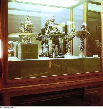 Moor with Emerald Plate holding a shallow dish with green emeralds in a glass display case