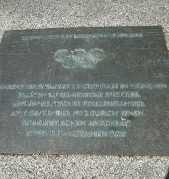 Klagebalken memorial plaque with the Olympic rings and German inscription set into the ground.