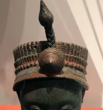 Bronze Head from Ife with fine vertical facial striations, closed eyes, and an elaborate headdress.