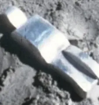 Fallen Astronaut figure lying on a textured grey surface, casting a sharp shadow.