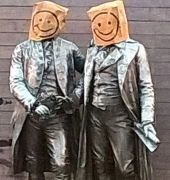 Goethe and Schiller Monument with both figures wearing paper bags over their heads with smiley faces drawn on them.