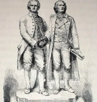 Goethe and Schiller Monument showing two standing male figures on a tiered stone pedestal, one holding a wreath and the other a rolled document.