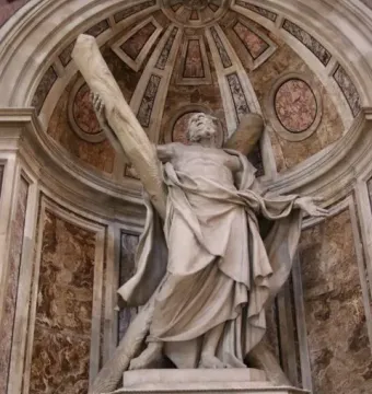 Saint Andrew sculpture in a vaulted niche, holding a large wooden beam and looking upward.