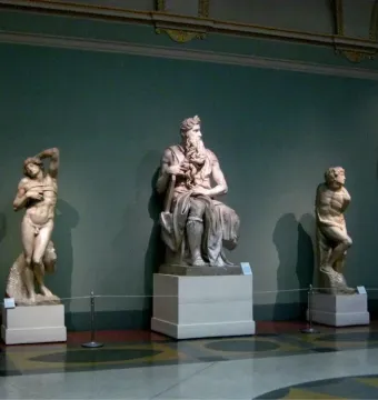 The Taddei Tondo relief sculpture displayed on a dark green museum wall.