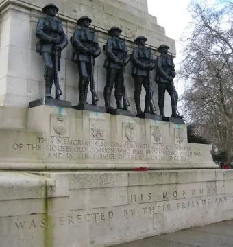 Guards Memorial with five dark soldier figures standing on a stone pedestal with engraved dedication text below.
