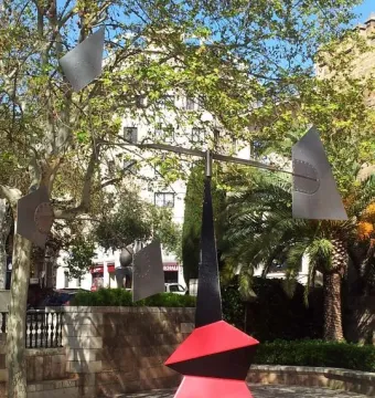 Nancy by Alexander Calder, a red and black metal sculpture with four suspended grey plates in a paved public square.