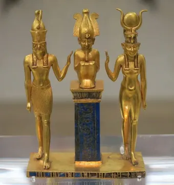 Osorkon II Triad showing three figures on a rectangular base, with a seated central figure atop a blue column flanked by two standing figures.