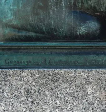 Bronze base of the Sleeping Lion sculpture with a Gladenbeck foundry inscription on a granite pedestal.