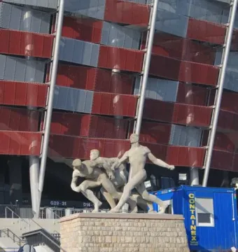 Sztafeta sculpture showing three male figures in dynamic running poses on a stone pedestal.