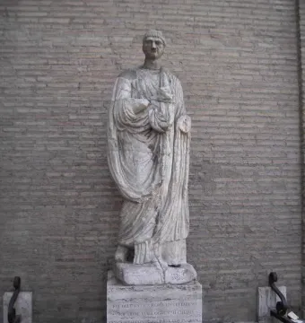 Abbot Luigi, a weathered stone statue of a robed male figure on an inscribed plinth.