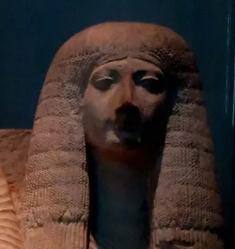 Head and upper torso of Amenia sculpture with heavily lidded eyes and a large textured wig