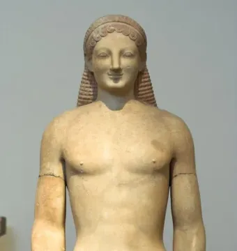 Kouros marble statue of a nude male figure with an archaic smile, long ridged hair, and a missing left forearm.